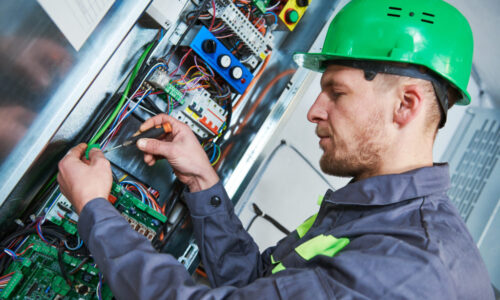 Elevator installation and maintenance. lift machinist electrician worker adjusting eelectronic control panel in engine room